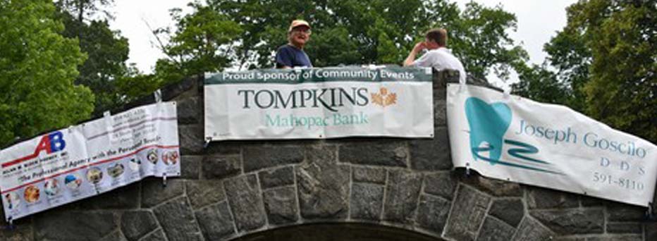 Stone bridge over a creek with sponsor signs hanging from it